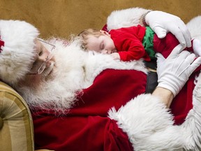 Five-week-old Arabella Sidwell takes a nap on Santa Claus while parents, Trevor and Natasha Sidwell, keep close by at the Rideau Centre Saturday December 13, 2014.