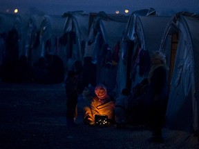 An elderly Syrian Kurdish refugee woman from the Kobani area, warms up by a fire at a  camp in Suruc, on the Turkey-Syria border Monday, Nov. 10, 2014. Kobani, also known as Ayn Arab, and its surrounding areas, has been under assault by extremists of the Islamic State group since mid-September and is being defended by Kurdish fighters.