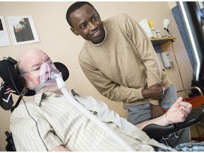 Howard Hunter , 63, an engineer who has ALS, uses an expensive, computer that allows him to use his eye movement for control.  Saint-Vincent Hospital's assistive technologist, Bocar NDiaye, right, has found less costly technology to help other patients.