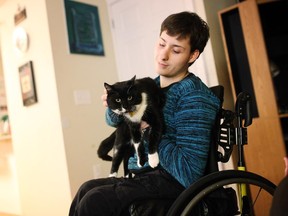 Jean-Luc St-Amour plays with his cat Leo, after it was returned to him Thursday evening at his Orleans home.