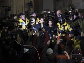 Police try to clear at path as Jian Ghomeshi makes his way through a mob of media with his lawyer Marie Henein (right) at a Toronto court Wednesday, November 26, 2014. T