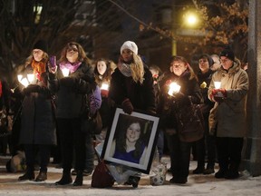 Kimberly Scobie, holding a portrait of Donna Jones, who was murdered by her husband five years ago, was among the dozens who gathered at the Women's Monument in Minto Park for a candlelight vigil to commemorate the lives of women killed due to male violence. This year marks the 25th anniversary of the Montreal Massacre, where 14 women were killed at the Ecole Polytechnique.