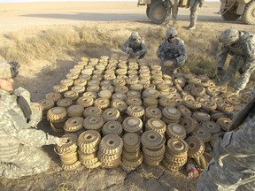 U.S. Army Soldiers of the 789th Ordnance Company prepare a cache of landmines, mortars, and 107mm rockets to be disposed of by a high explosives charge, April 13. The cache was found in the Besmaya Region Southeast of Baghdad, Iraq earlier in the day.