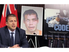 Ombudsman André Marin is seen at the Ontario legislature in Toronto in June 2013 following the release of his report into jail guard brutality. Behind him is a photograph of prisoner Jean Paul Rheaume taken after he was beaten and stomped at the Ottawa-Carleton Detention Centre.