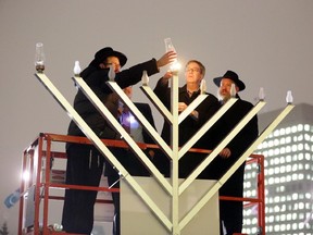 Mayor Jim Watson, second from right, lights a 12-foot Menorah with some help from Rabbis Chaim Boyarsky, Reuven Bulka and Rabbi David Hayes.