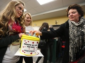 Megan McCoy, left, and Nicole McKenna receive a donation from Patricia Donaldson to the fund for Neil Doef at Friday night's Smith Falls Bears hockey game at Smiths Falls Memorial Centre.