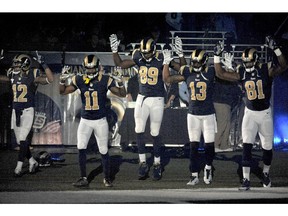 Members of the St. Louis Rams raise their arms in awareness of the events in Ferguson, Mo.,  as they walk onto the field during introductions before an NFL football game against the Oakland Raiders, Sunday, Nov. 30, 2014, in St. Louis.  The players said after the game, they raised their arms in a "hands up" gesture to acknowledge the events in Ferguson.