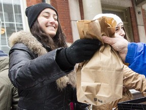 Monique Amar, left and Mathiane Vachon-Gravel were among 25 students from Carleton University and University of Ottawa volunteered with Feed The Homeless By U to hand out over 150 lunches in 25 minutes at noon outside The Ottawa Mission Wednesday, December 10, 2014.