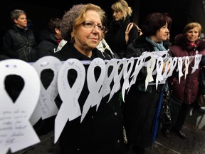 Ida Canci, Carolina Eleazzaro and Jose Catarinacci from the Centre des Femmes Italiennes de Montreal hold a line of 22 white ribbons, one for each year since the murder of 14 female students at Ecole Polytechnique, at a rally against violence against women outside the Palais de Justice in Montreal Tuesday December 6, 2011.