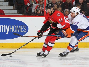 Erik Karlsson #65 of the Ottawa Senators stickhandles the puck against Matt Martin #17 of the New York Islanders.