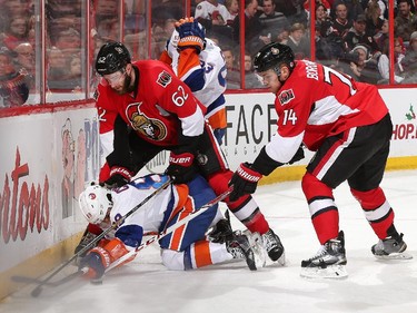 Eric Gryba #62 and Mark Borowiecki #74 of the Ottawa Senators knock Cory Conacher #89 of the New York Islanders to the ice and off the puck.