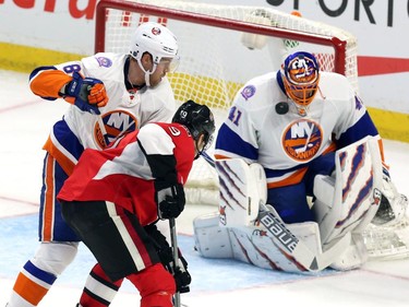 New York Islanders goaltender Jaroslav Halak (41) blocks the puck with his face mask as teammate Griffin Rienhart (8) and Ottawa Senators' Milan Michalek (9) look on during second period NHL hockey action.