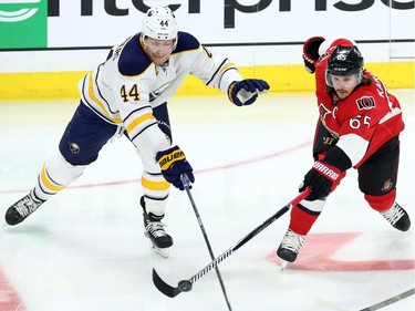 Ottawa Senators' Erik Karlsson (65) and Buffalo Sabres' Nicolas Deslauriers both reach for the puck during second period NHL hockey action.