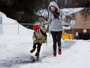 Raven Chopowick holds her son Paxton's hand as they navigate a slippery sidewalk on the way to school as the region experiences freezing rain and melting snow conditions before it was expected to freeze over later in the day.