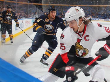 Erik Karlsson #65 of the Ottawa Senators controls the puck in the corner against Chris Stewart #80 of the Buffalo Sabres.