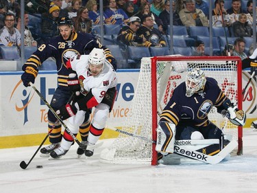 Milan Michalek #9 of the Ottawa Senators is defended by Zemgus Girgensons #28 and Jhonas Enroth #1 of the Buffalo Sabres.