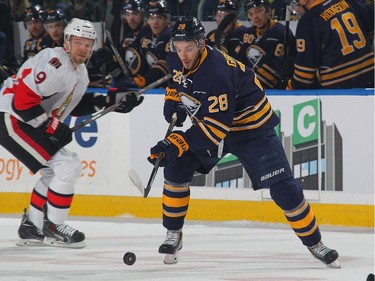 Zemgus Girgensons #28 of the Buffalo Sabres looks to control the puck against Milan Michalek #9 of the Ottawa Senators.