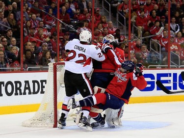 Erik Condra #22 of the Ottawa Senators collides with goalie Braden Holtby #70 and Jack Hillen #38 of the Washington Capitals after scoring a second period goal.