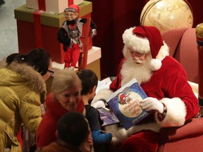 Santa Claus hands out children's books to youngsters during the Mayor's 14th Annual Christmas Celebration at Ottawa City Hall on Saturday, December 6, 2014.