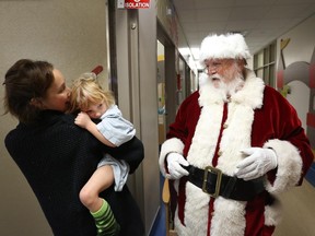 Santa Claus visits a very shy four-year-old Jenna Richmire, who is held by her mom, Barb. This is Jenna's second Christmas at CHEO.