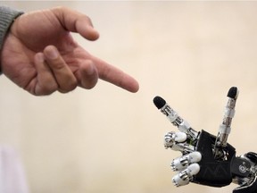 A man moves his finger toward the finger of humanoid robot iCub during the 2014 IEEE-RAS International Conference on Humanoid Robots in Madrid on November 18, 2014. The conference theme "Humans and Robots Face-to-Face" confirms the growing interest in the field of human-humanoid interaction and cooperation, especially during daily life activities in real environments.