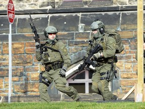 An RCMP intervention team run next to a Parliament building in Ottawa Wednesday Oct.22, 2014. A Canadian soldier standing guard at the National War Memorial in Ottawa has been shot by an unknown gunman and there are reports of gunfire inside the halls of Parliament. THE CANADIAN PRESS/Adrian Wyld