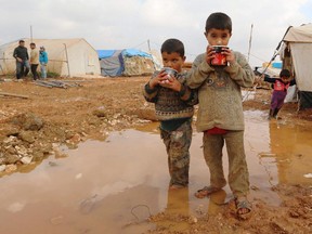 Displaced Syrian children stand in muddy water after heavy rains in the Bab Al-Salama camp for people fleeing the violence in Syria on December 11, 2014, on the border with Turkey. Aid workers fear a major humanitarian crisis for millions of Syrian refugees in the Middle East after funding gaps forced the United Nations to cut food assistance for 1.7 million people.