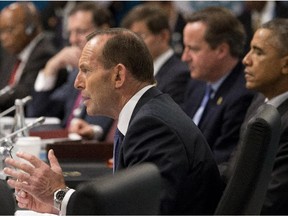In this Nov 15, 2014 photo, Australian Prime Minister Tony Abbott addresses leaders including U.S. President Barack Obama, right, and British Prime Minister David Cameron, second right, during a plenary session of the G-20 summit in Brisbane, Australia. Abbott, who rose to power in large part by opposing a tax on greenhouse gas emissions, is finding his country isolated like never before on climate change as the U.S., China and other nations signal new momentum for action.