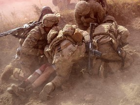 US Army soldiers protect a wounded comrade from dust and smoke flares after an Improvised Explosive Device (IED) blast during a patrol near Baraki Barak base in Logar Province on October 13, 2012.