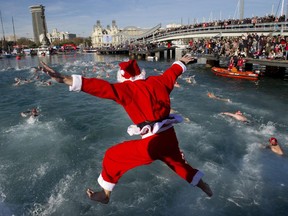 A participant wearing a Santa Clause costume jumps into the water during the105th edition of the Copa Nadal (Christmas Cup) in Barcelona's Port Vell on December 25, 2014. The traditional 200-meter Christmas swimming race gathered around 400 participants on Barcelona's old harbour.