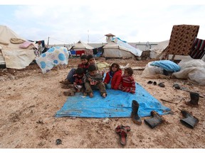 Displaced Syrian children sit on a tarp after heavy rains in the Bab Al-Salama camp for people fleeing the violence in Syria on December 11, 2014, on the border with Turkey. Aid workers fear a major humanitarian crisis for millions of Syrian refugees in the Middle East after funding gaps forced the United Nations to cut food assistance for 1.7 million people.