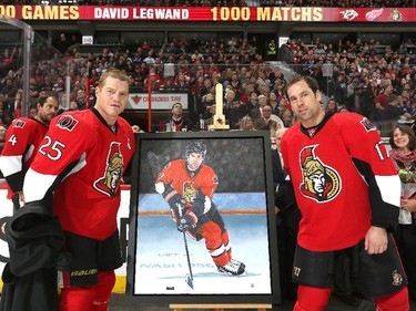 David Legwand #17 of the Ottawa Senators is presented with a painting by teammate Chris Neil #25 during a ceremony to celebrate his 1000 career NHL games prior to playing the Vancouver Canucks at Canadian Tire Centre on December 7, 2014 in Ottawa, Ontario, Canada.