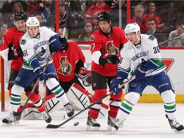 Derek Dorsett #51 and Jannik Hansen #36 of the Vancouver Canucks attempt to tip the puck for a scoring chance against Cody Ceci #5 and David Legwand #17 of the Ottawa Senators at Canadian Tire Centre on December 7, 2014 in Ottawa, Ontario, Canada.