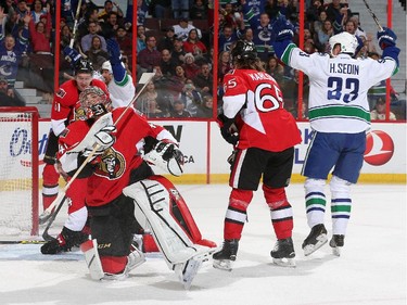 Henrik Sedin #33 of the Vancouver Canucks celebrates a first period goal against Craig Anderson #41 of the Ottawa Senators as Mark Stone #61 and Erik Karlsson #65 of the Ottawa Senators look on during an NHL game at Canadian Tire Centre on December 7, 2014 in Ottawa, Ontario, Canada.