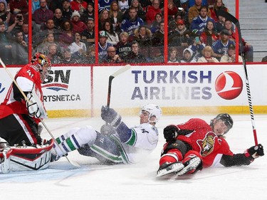 Alex Burrows #14 of the Vancouver Canucks crashes into Craig Anderson #41 of the Ottawa Senators after being checked by Erik Karlsson #65 of the Ottawa Senators during an NHL game at Canadian Tire Centre on December 7, 2014 in Ottawa, Ontario, Canada.