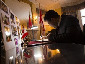 Wahid Sheerzuy, first secretary of the Embassy of the Islamic Republic of Afghanistan, signs a book of condolences at the Pakistan High Commission in Ottawa Wednesday, December 17, 2014. (Darren Brown/Ottawa Citizen)