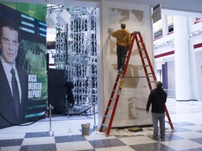 Workers scrape a wall which had a publicity photo of former CBC radio host Jian Ghomeshi in the broadcasting corporation's Toronto offices on Monday October 27, 2014.