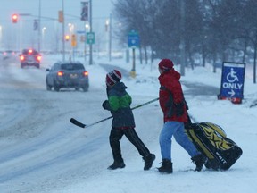 A boy and father walk back to their car after a fresh snowfall after a hockey game at Canadian Tire Centre.