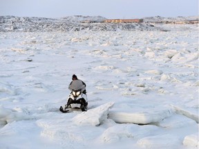 A snowmobiler makes his way through the ice heaves in Frobisher Bay in Iqaluit, Nunavut on December 10, 2014.
