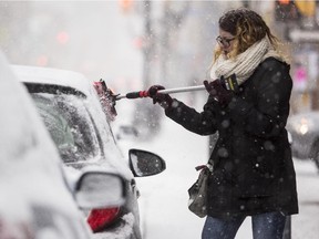A woman brushes the snow of her car on Bank Street during the first snow storm of the year Saturday, January 3, 2015.