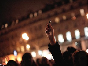 A woman holds up a pen during a gathering in solidarity of the victims of a terror attack against French satirical newspaper Charlie Hebdo in Paris, Wednesday, Jan. 7, 2015. Masked gunmen stormed the Paris offices of a weekly newspaper that caricatured the Prophet Muhammad, methodically killing 12 people Wednesday, including the editor, before escaping in a car. It was France's deadliest postwar terrorist attack.