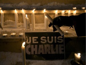 A woman lights a candle near a sign that read in French "I am Charlie" during a demonstration in solidarity with those killed in an attack at the Paris offices of the weekly newspaper Charlie Hebdo  in Kosovo capital Pristina, Wednesday, Jan. 7, 2015.