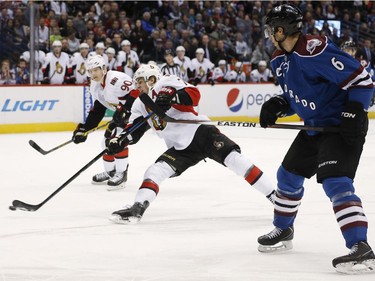 Colorado Avalanche defenseman Erik Johnson, right, is called for penalty by using his stick to stop Ottawa Senators center Kyle Turris, center, from rushing the net for a shot with right wing Alex Chiasson during the second period of an NHL hockey game Thursday, Jan. 8, 2015, in Denver.