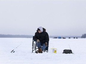 An ice fisherman off Petrie Island patiently watches his lines for signs of a bite.