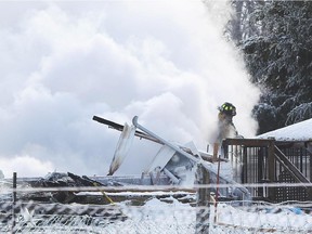 An Ottawa firefighter in the smoke of what is left of a house still smoking at 6042 Dobson Lane near Ottawa, January 07, 2015.