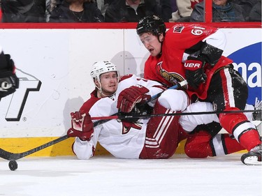 Oliver Ekman-Larsson #23 of the Arizona Coyotes falls to the ice with Mark Stone #61 of the Ottawa Senators into the boards at Canadian Tire Centre on January 31, 2015 in Ottawa, Ontario, Canada.