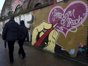 A pedestrian walks past graffiti that reads "Je suis Charlie" (I am Charlie), referring to the movement in solidarity with the victims of the attack on the Paris offices of the satirical French publication Charlie Hebdo, and "Freedom of speech" in east London on January 10, 2015.