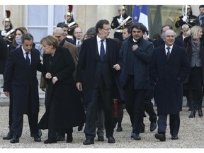 Carla Bruni-Sarkozy, back left, former French President Nicolas Sarkozy, second from left, German Chancellor Angela Merkel, third from left, Spanish Prime Minister Mariano Rajoy, center, and Danish Prime Minister Helle Thorning-Schmidt, back far right, leave the Elysee Palace to board a bus to join a rally, Paris, Sunday, Jan. 11, 2015. A rally of defiance and sorrow, protected by an unparalleled level of security, on Sunday will honor the 17 victims of three days of bloodshed in Paris that left France on alert for more violence.