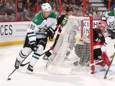 Jason Spezza #90 of the Dallas Stars controls the puck behind the net of Robin Lehner #40 of the Ottawa Senators.