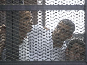 A picture taken on June 23, 2014 at the police institute near Cairo's Tora prison, shows Al-Jazeera news channel's Australian journalist Peter Greste (L) and his colleagues, Egyptian-Canadian Mohamed Fadel Fahmy (C) and Egyptian Baher Mohamed, listening to the verdict inside the defendants cage during their trial for allegedly supporting the Muslim Brotherhood.